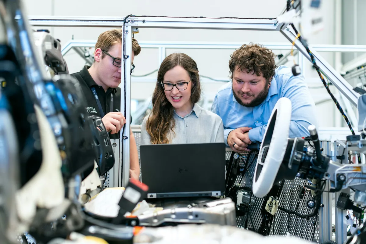 Engineers reviewing live diagnostic data on a laptop beside an automotive test rig
